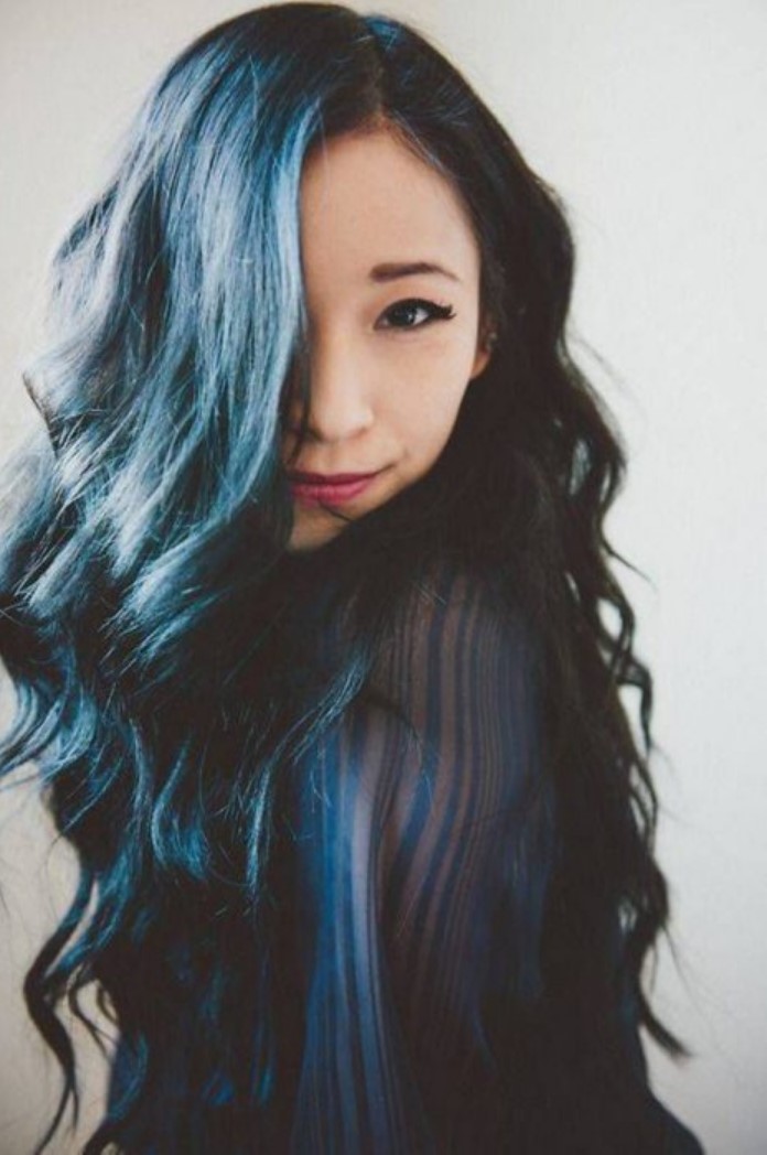 Girl covering her face with her long hair with highlights in blue