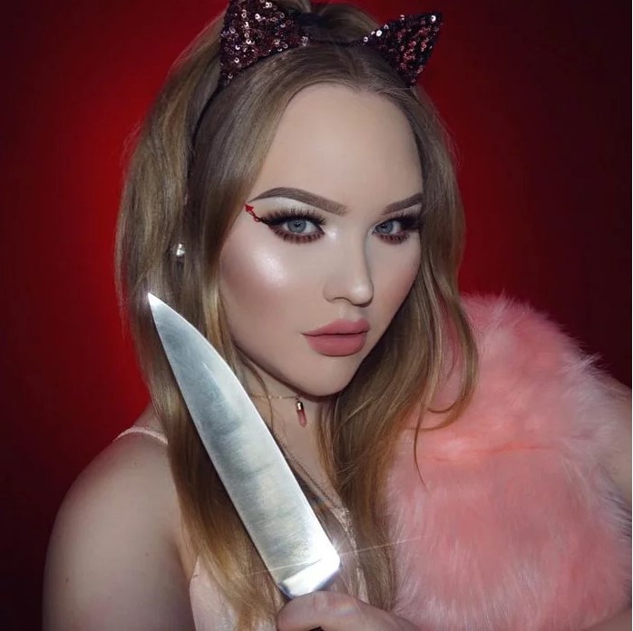 Woman with knife and devil makeup on eyes