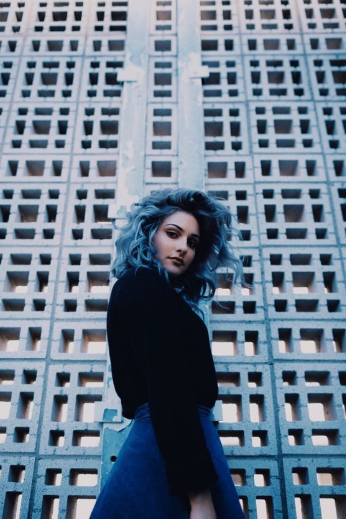 Girl modeling in front of a building, showing her blue sky hair