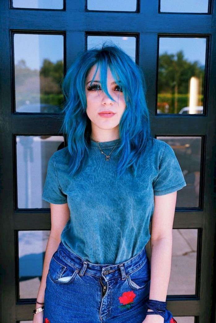 Girl posing in front of a glass door, showing her electric blue hair