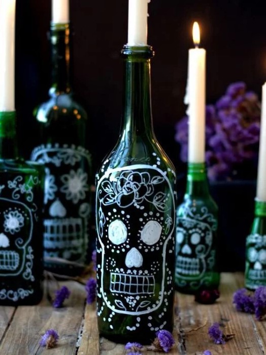 Candles in wine bottles decorated with skulls.